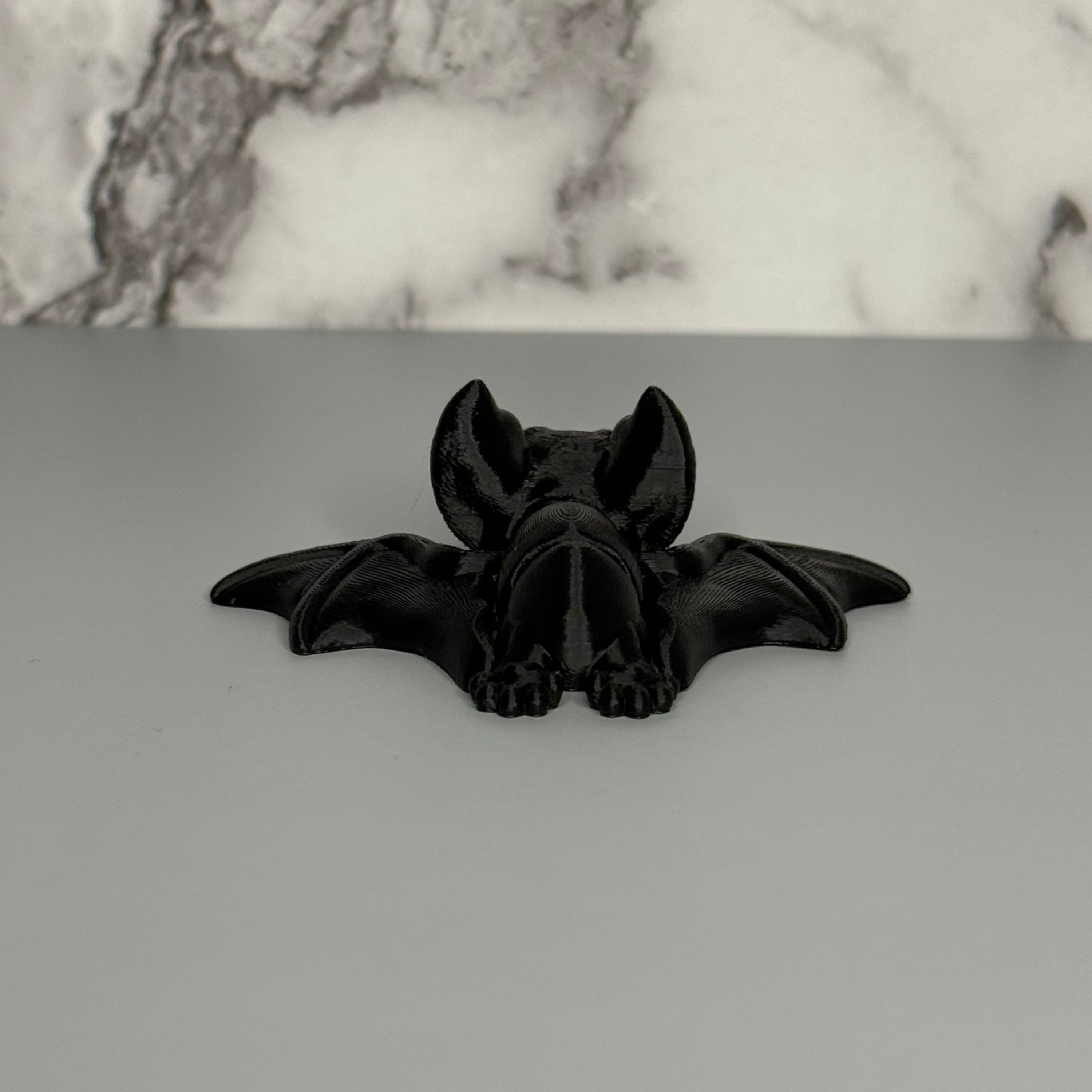 Black bat-shaped object on a gray surface with a marble background