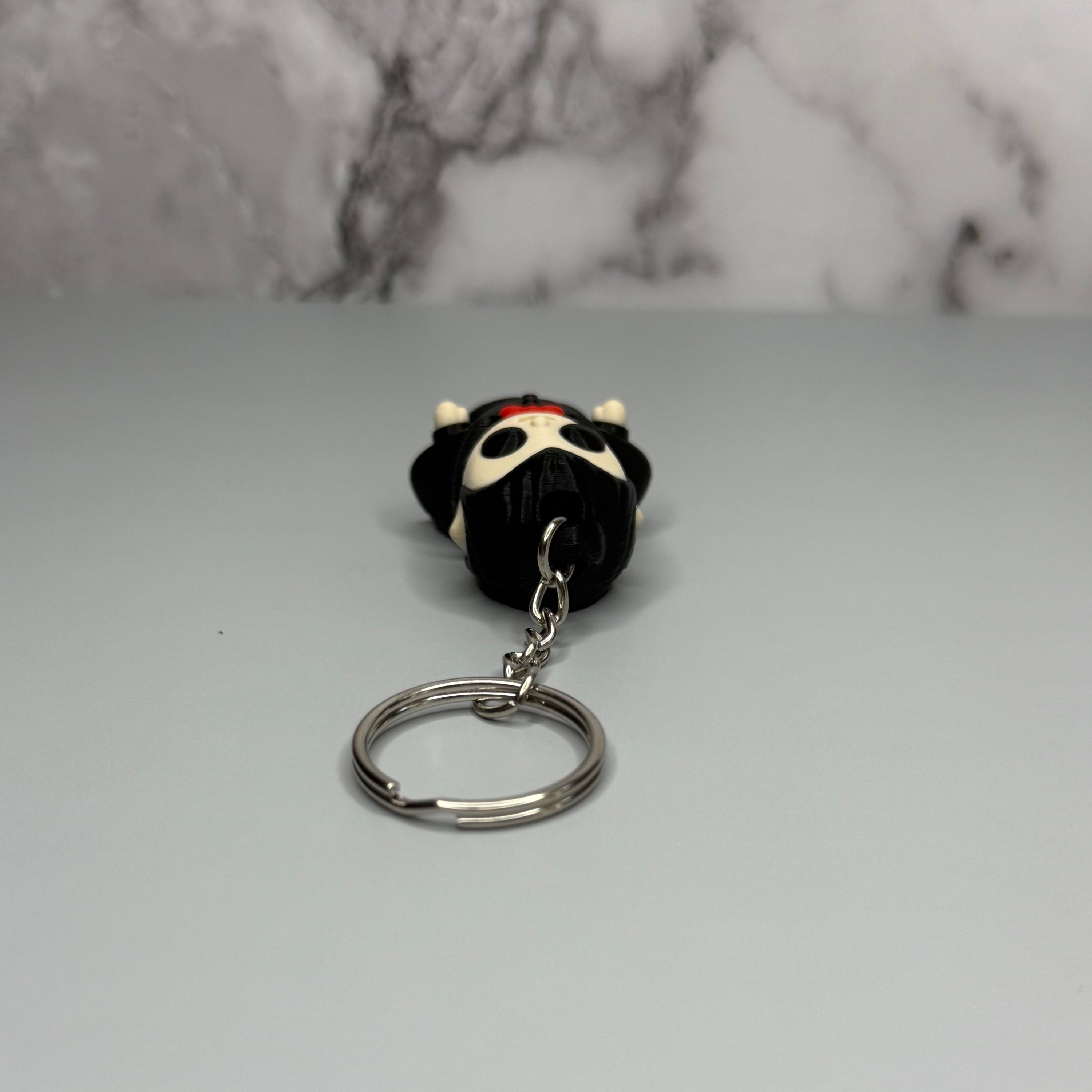 Top side of a keychain of a dracula vampire figure on a gray marble background