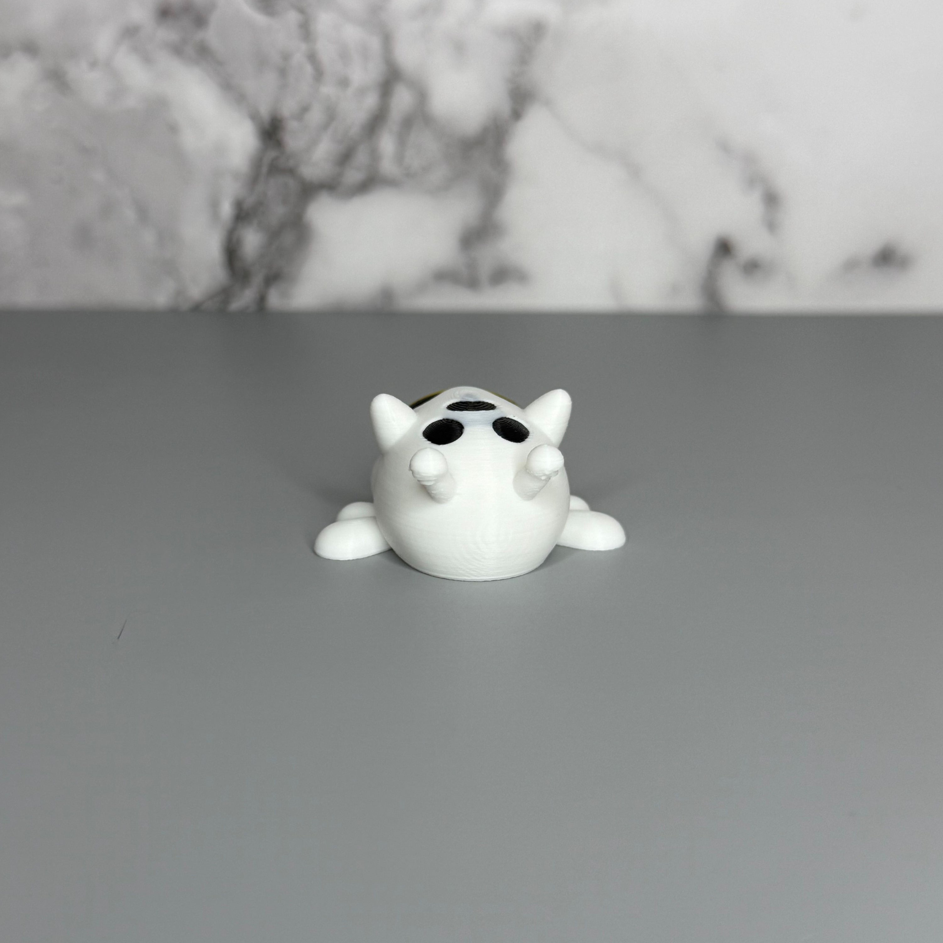 Top view of bee shaped ghost figure with white wings on gray marble background.