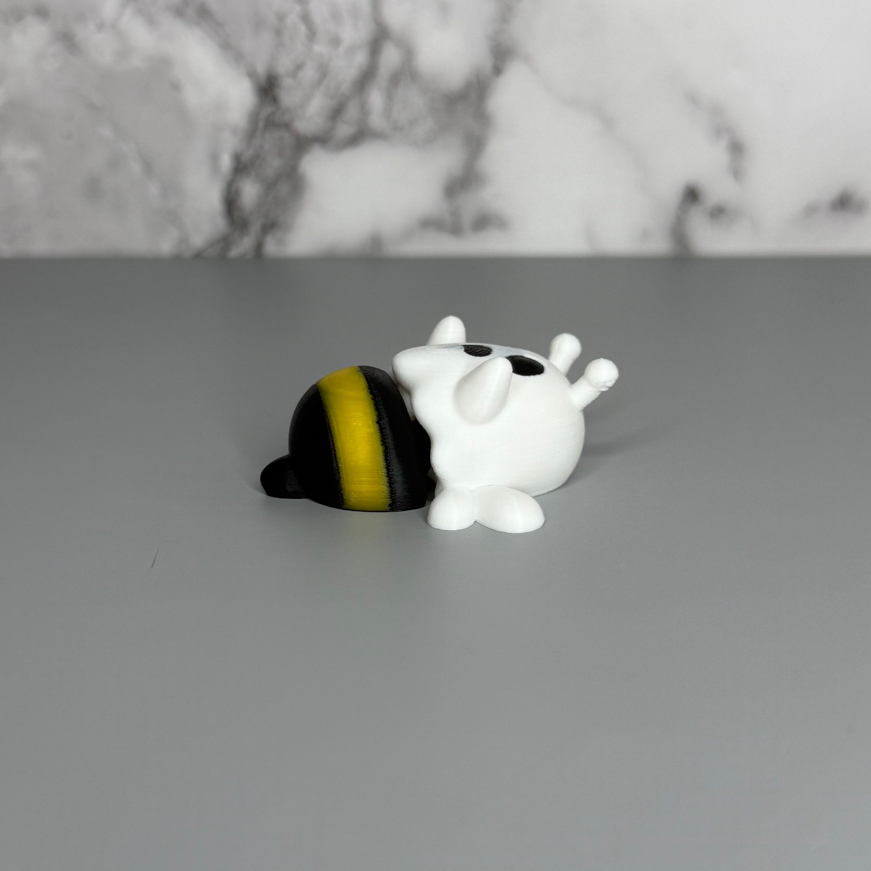 Ghost figure with white wings and a black and yellow bee-shaped lower body on a gray marble background.