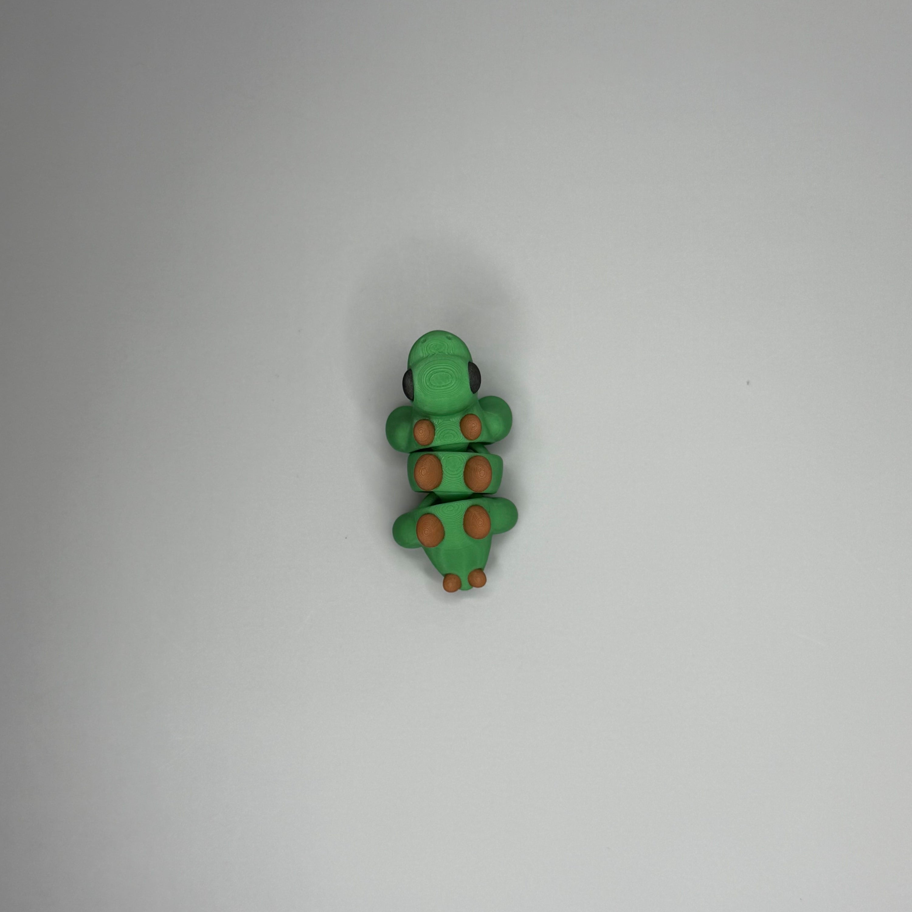 Green dinosaur-shaped object with brown spikes on a gray surface