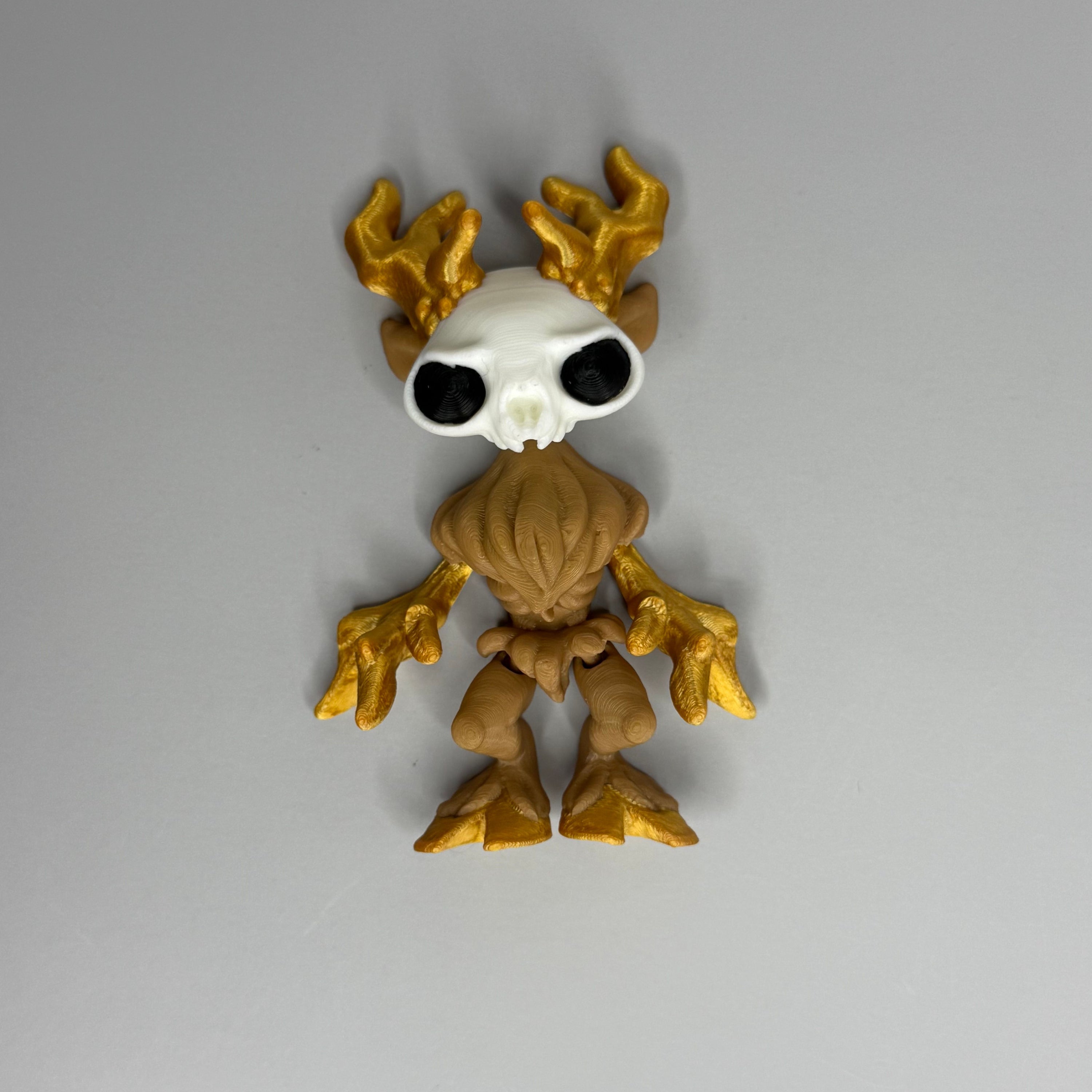 Figure of a wendigo with gold antlers, white face, brown body, and gold hands and hooves on a gray background
