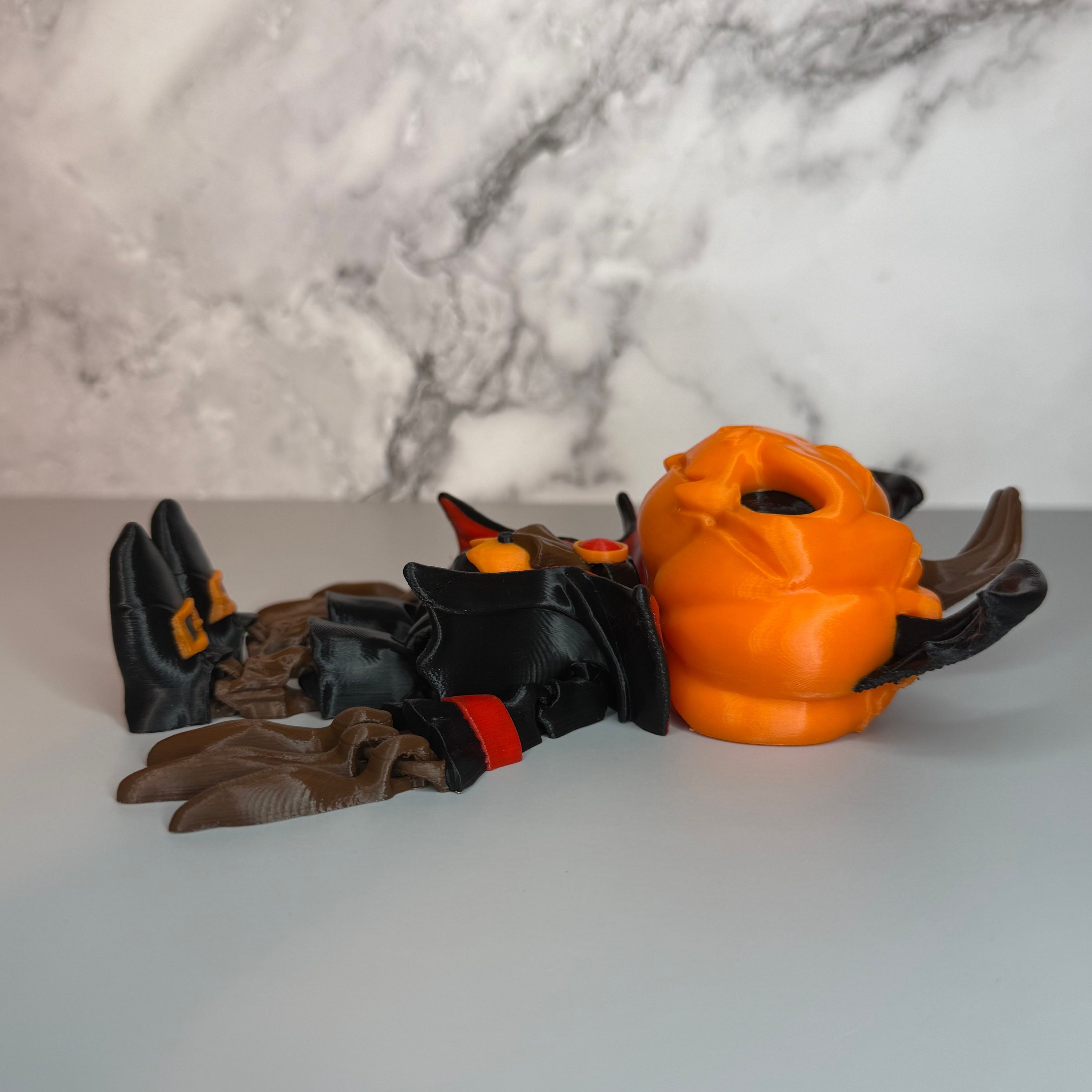Side view of a figure with a head of a pumpkin with bat wings on it, black and red suit, black shoes with orange buckles, and long brown fingers on a gray and marble background
