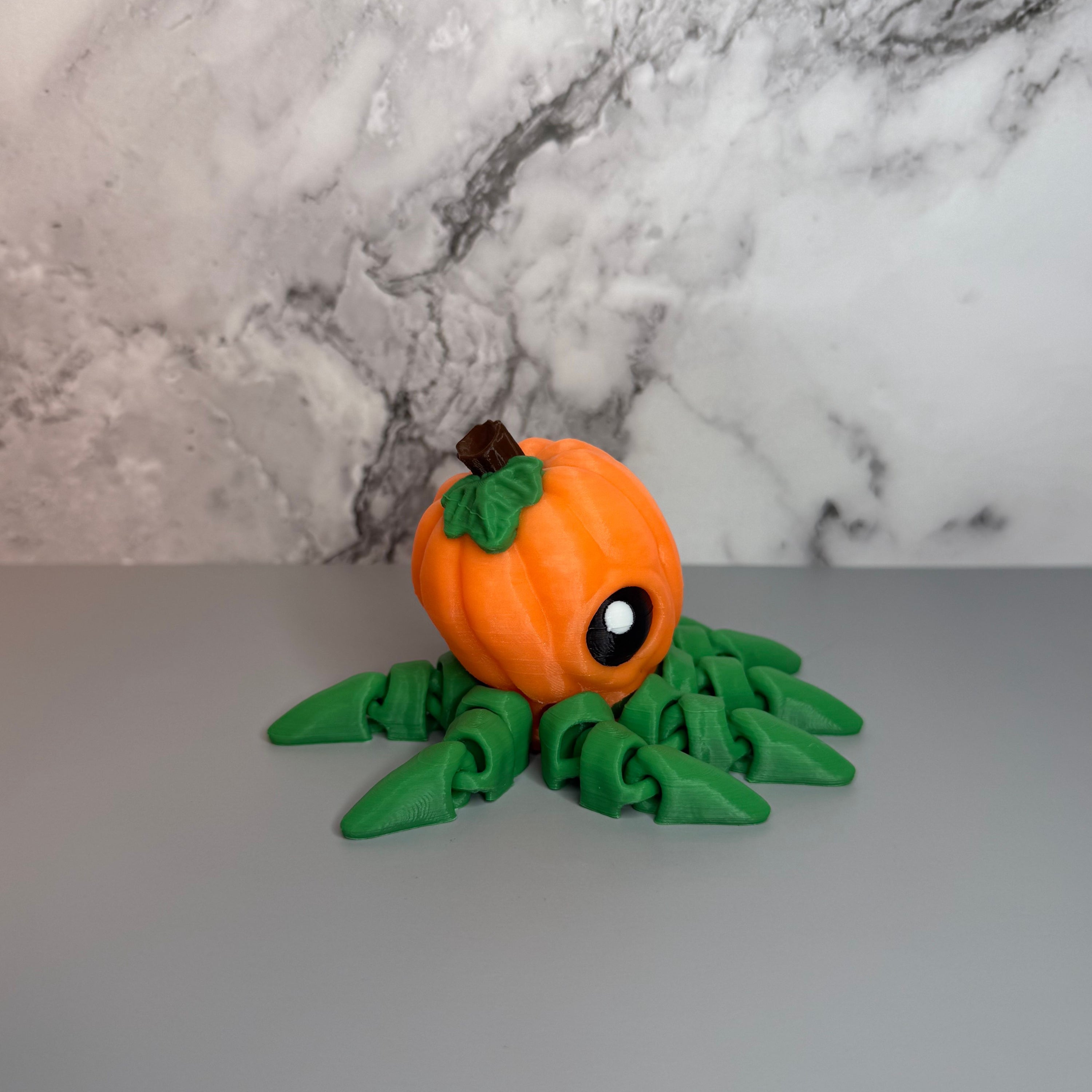 Octopus shaped orange pumpkin figure with green legs on a gray marble background.