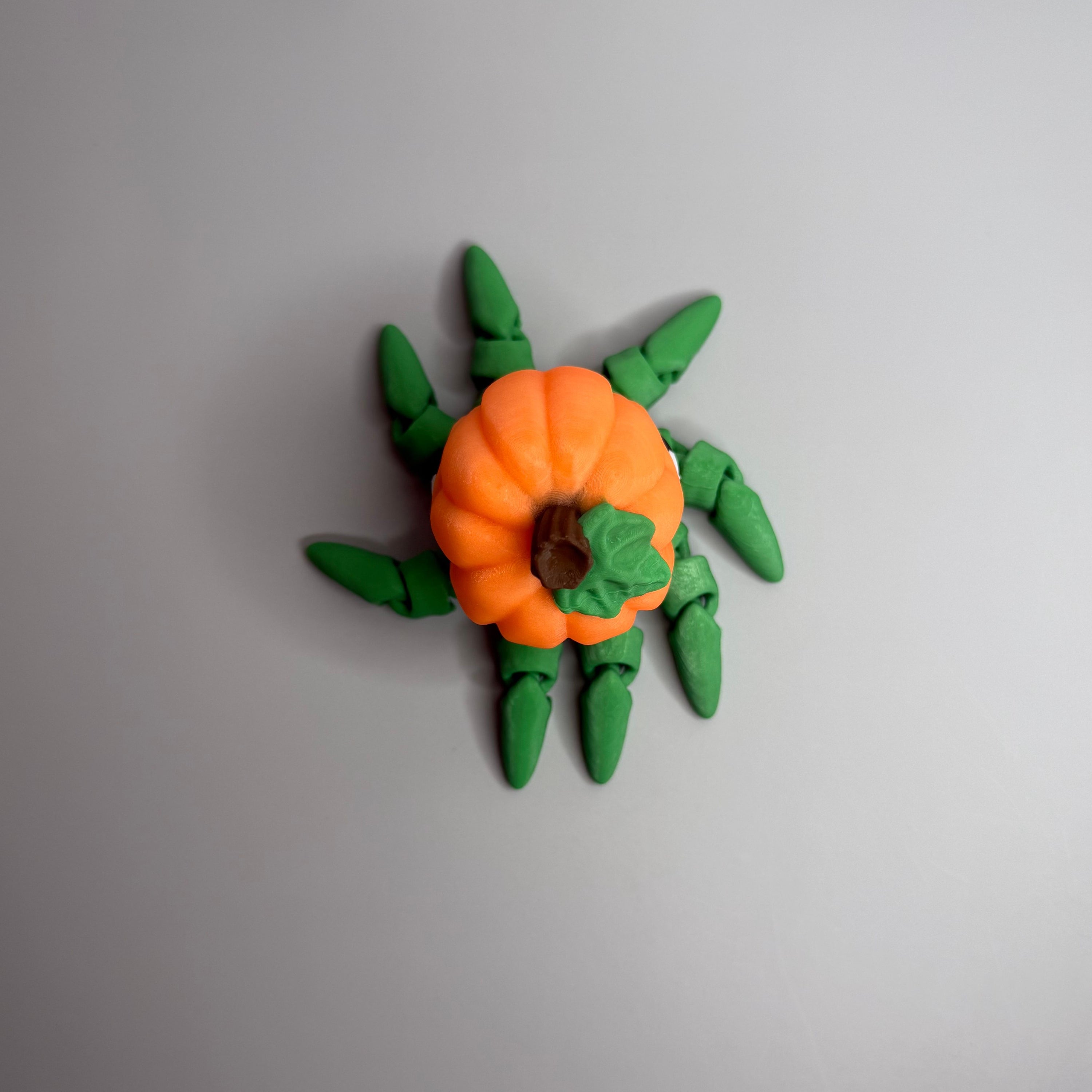 Octopus shaped orange pumpkin figure with green legs on a gray background.