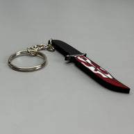 Keychain resembling a knife with a blood-stained blade on a gray background