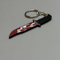 Keychain resembling a knife with a blood-stained blade on a gray background