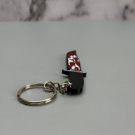 Keychain resembling a knife with a blood-stained blade on a gray background
