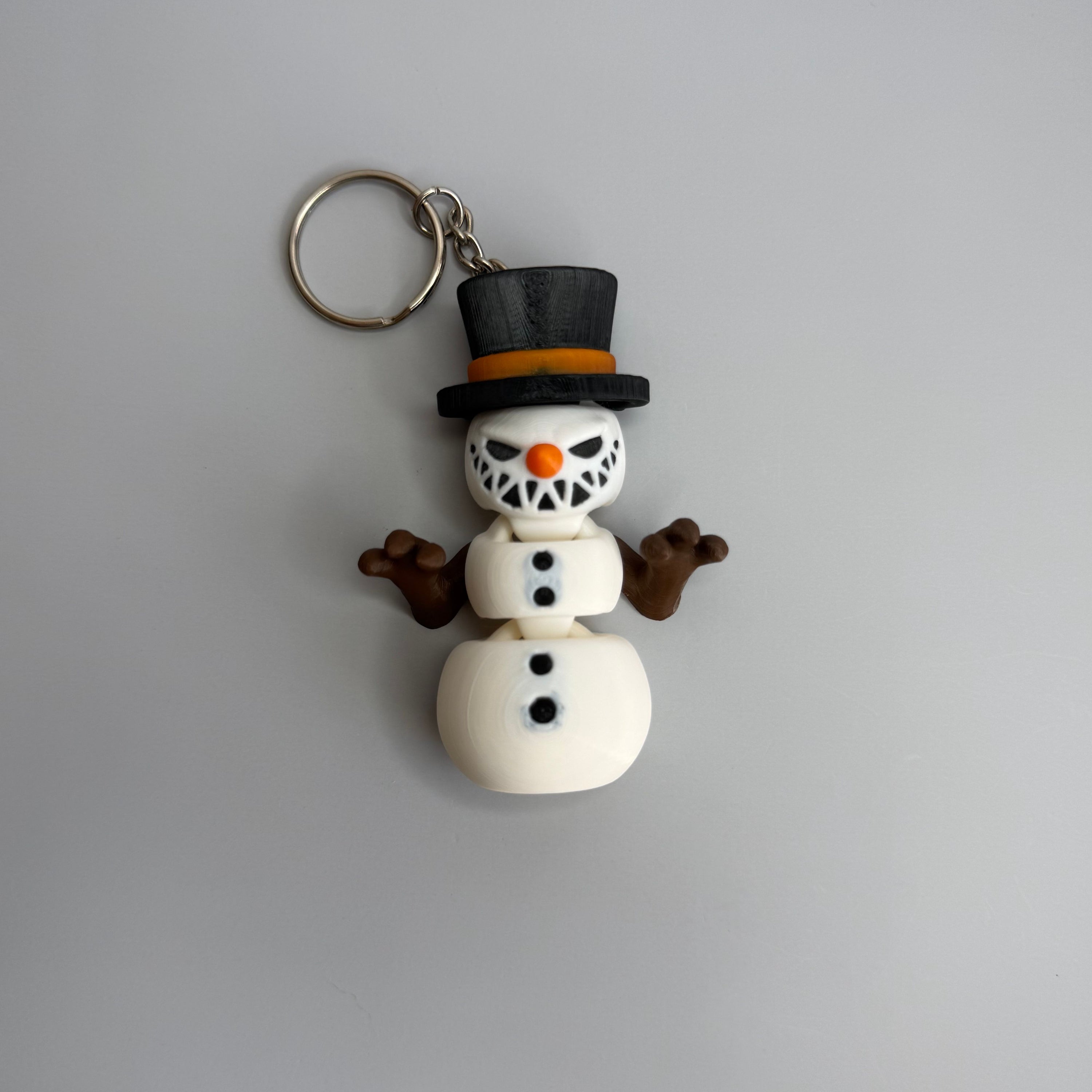Keychain of a small snowman with a sinister smile with black top hat on a gray background