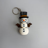 Keychain of a small snowman with a sinister smile with black top hat on a gray background
