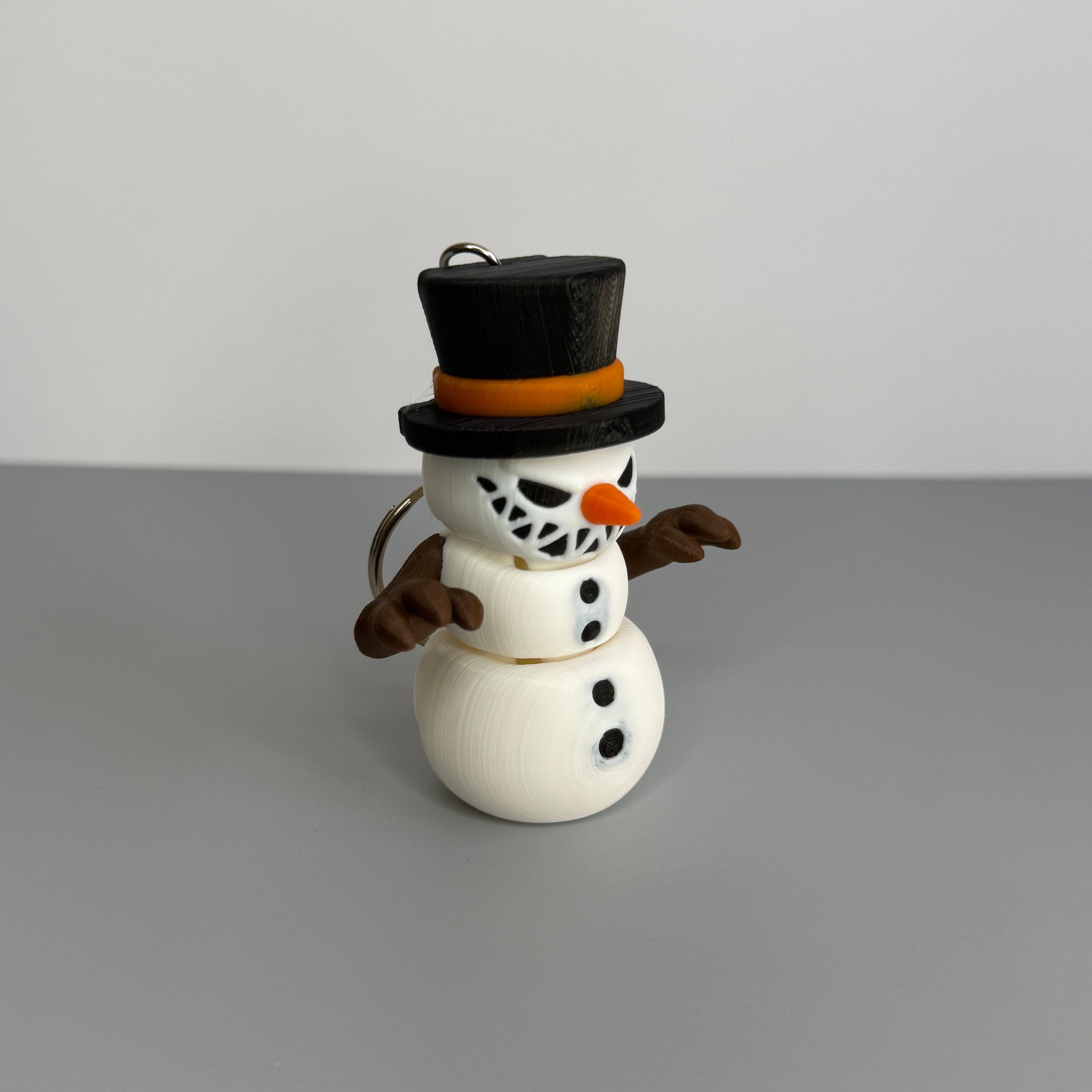 Keychain of a small snowman with a sinister smile with black top hat on a gray background