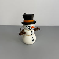 Keychain of a small snowman with a sinister smile with black top hat on a gray background