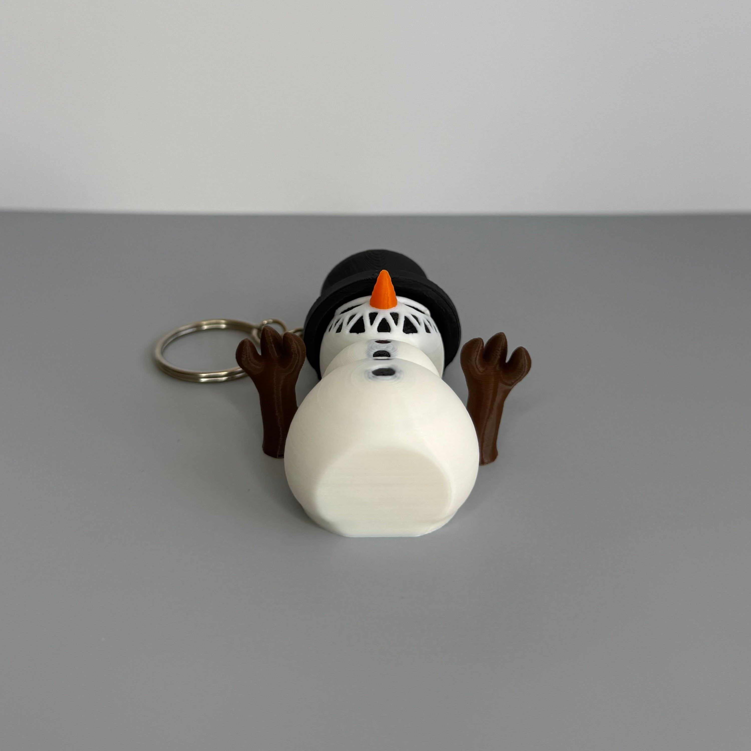 Snowman keychain with a carrot nose on a gray background