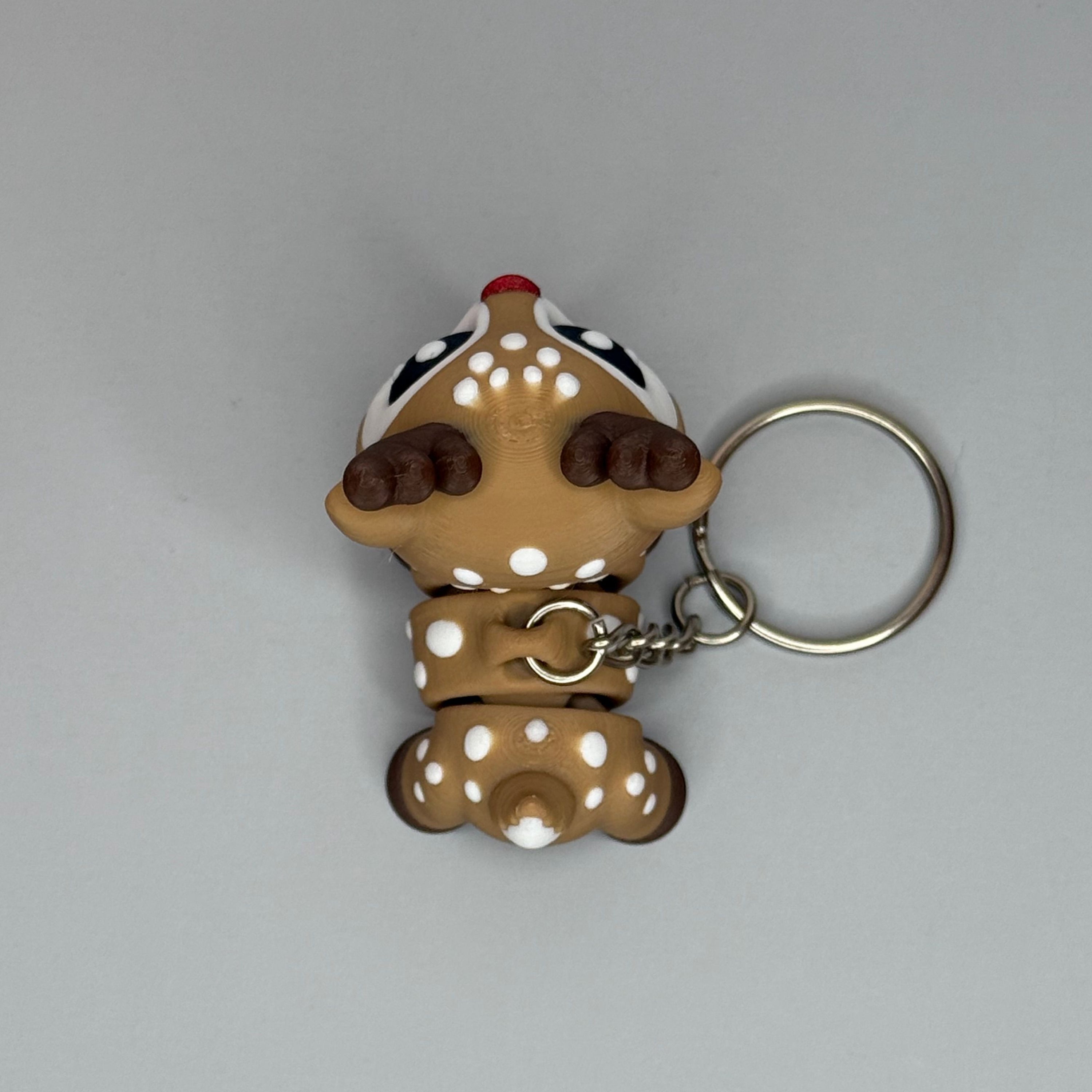 Top perspective of a reindeer-shaped keychain with a red, shimmer nose on a gray background