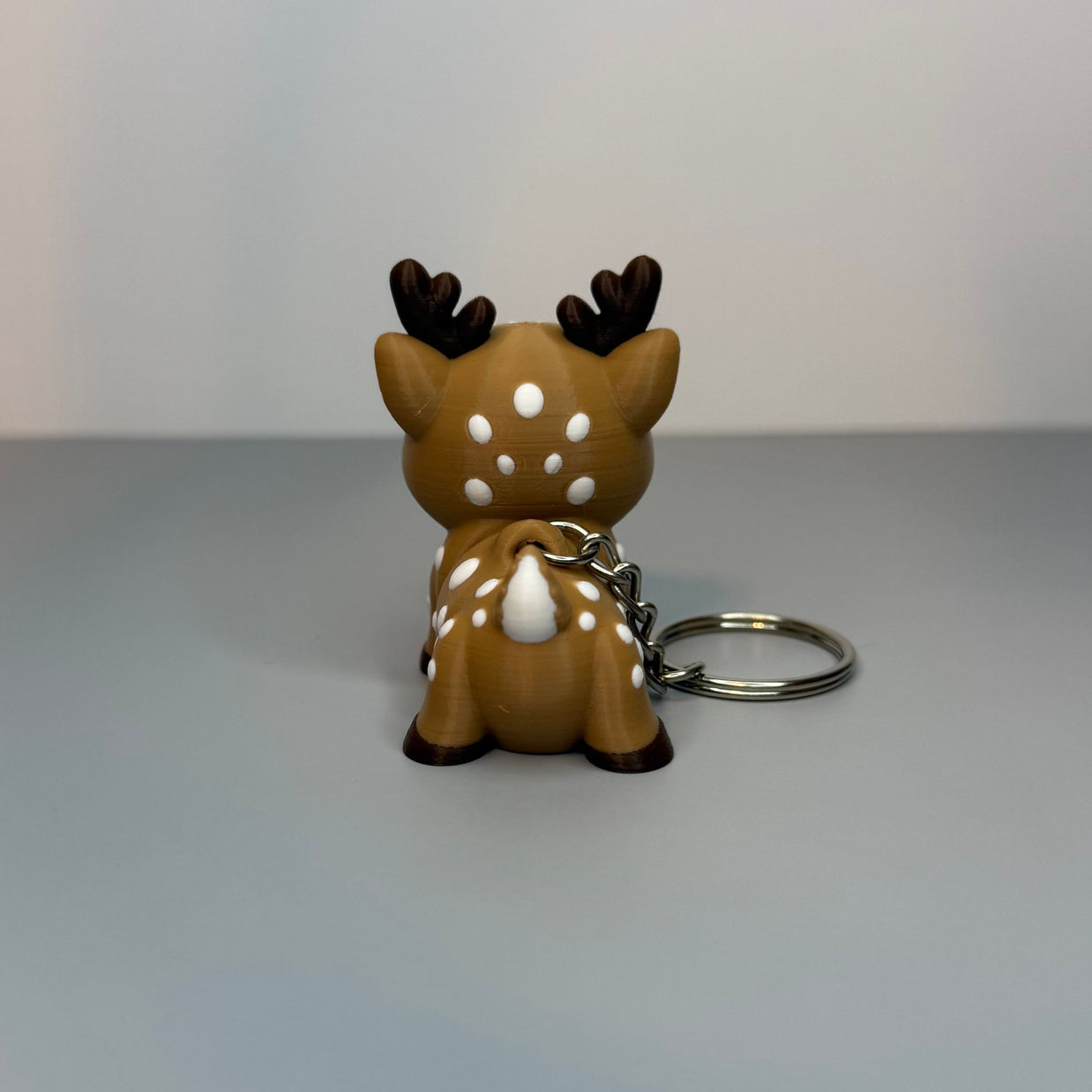 Backside of a reindeer-shaped keychain  on a gray background