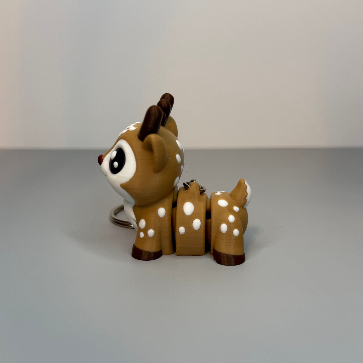 Small deer figurine with white spots on a gray surface