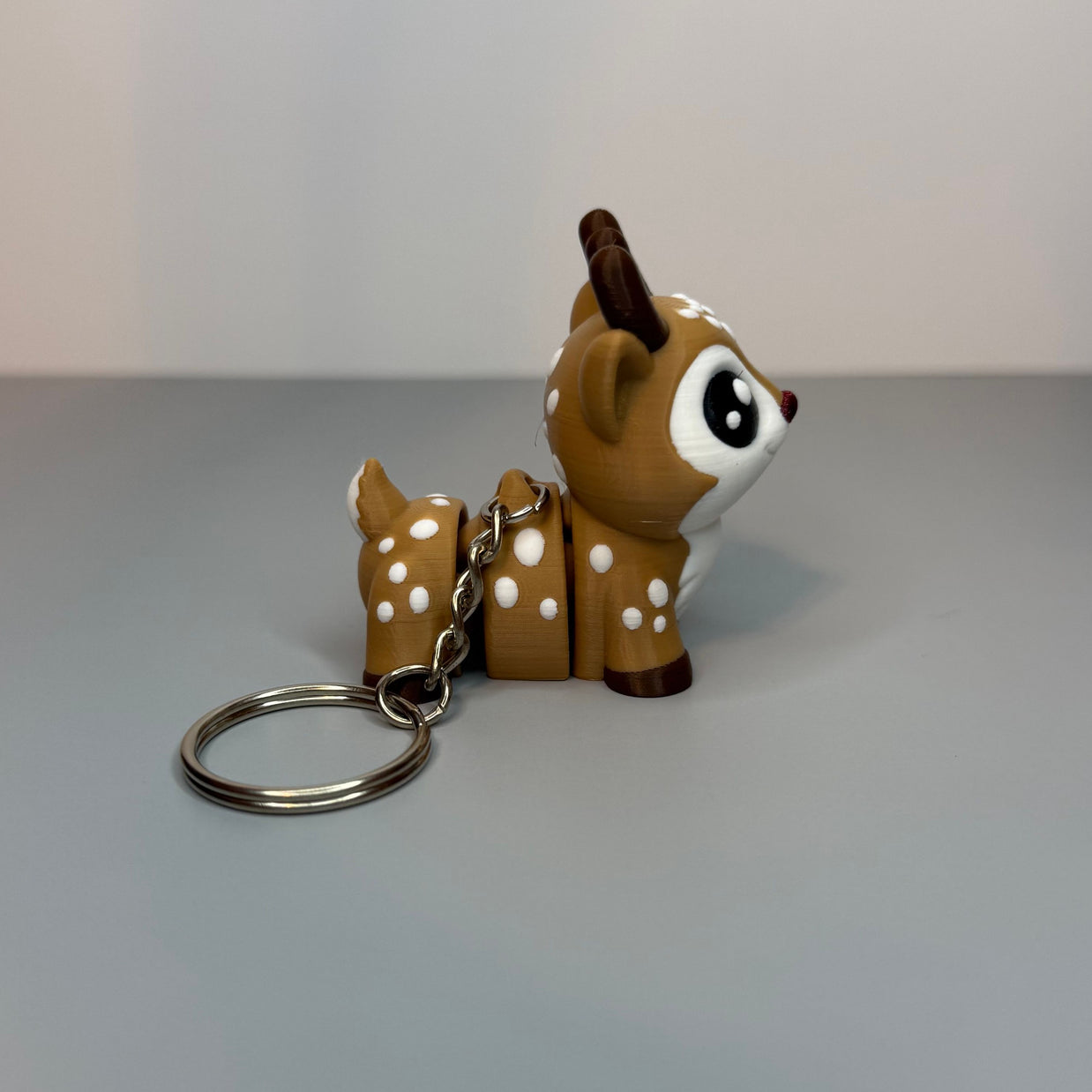 Deer-shaped keychain with white spots on a gray surface