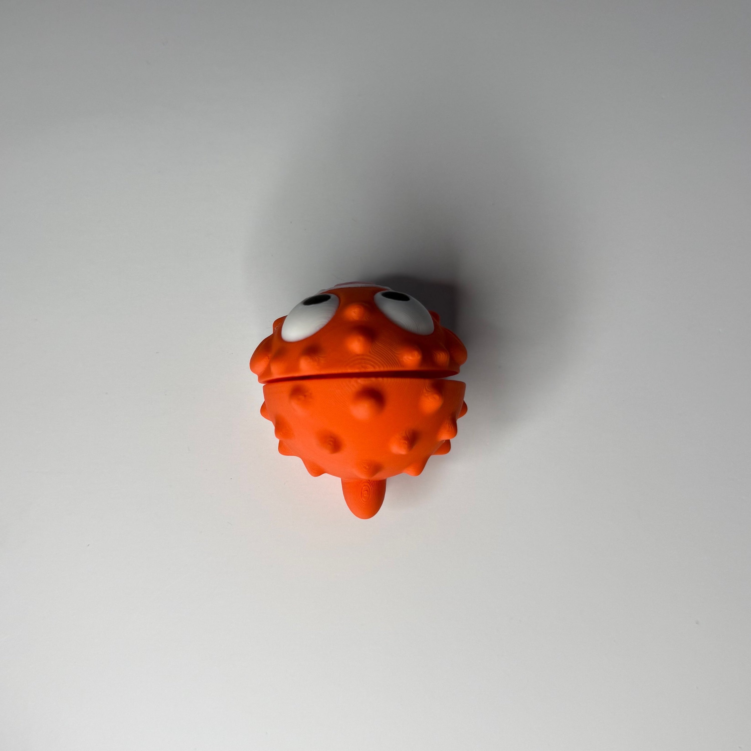 Topside of an orange and white puffer fish figure on a white background