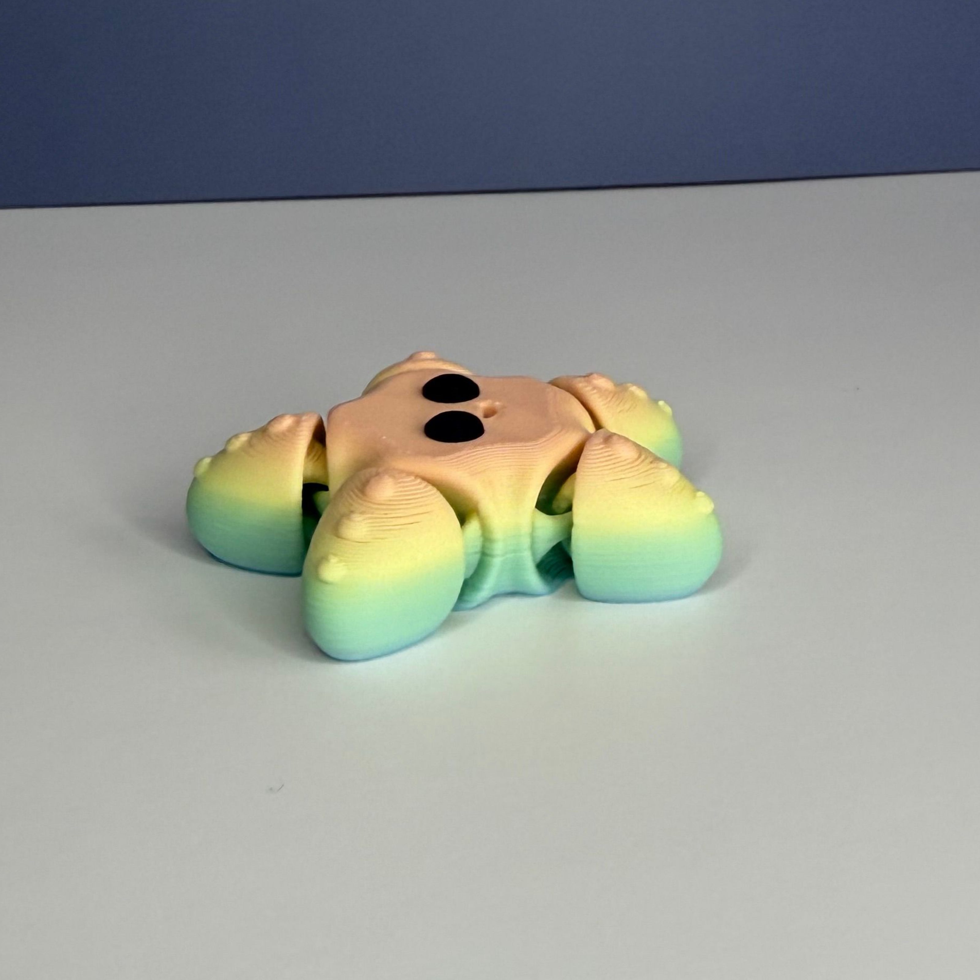 Side of a smiling star-shaped figure with a gradient rainbow color pattern and black eyes on a blue and white background
