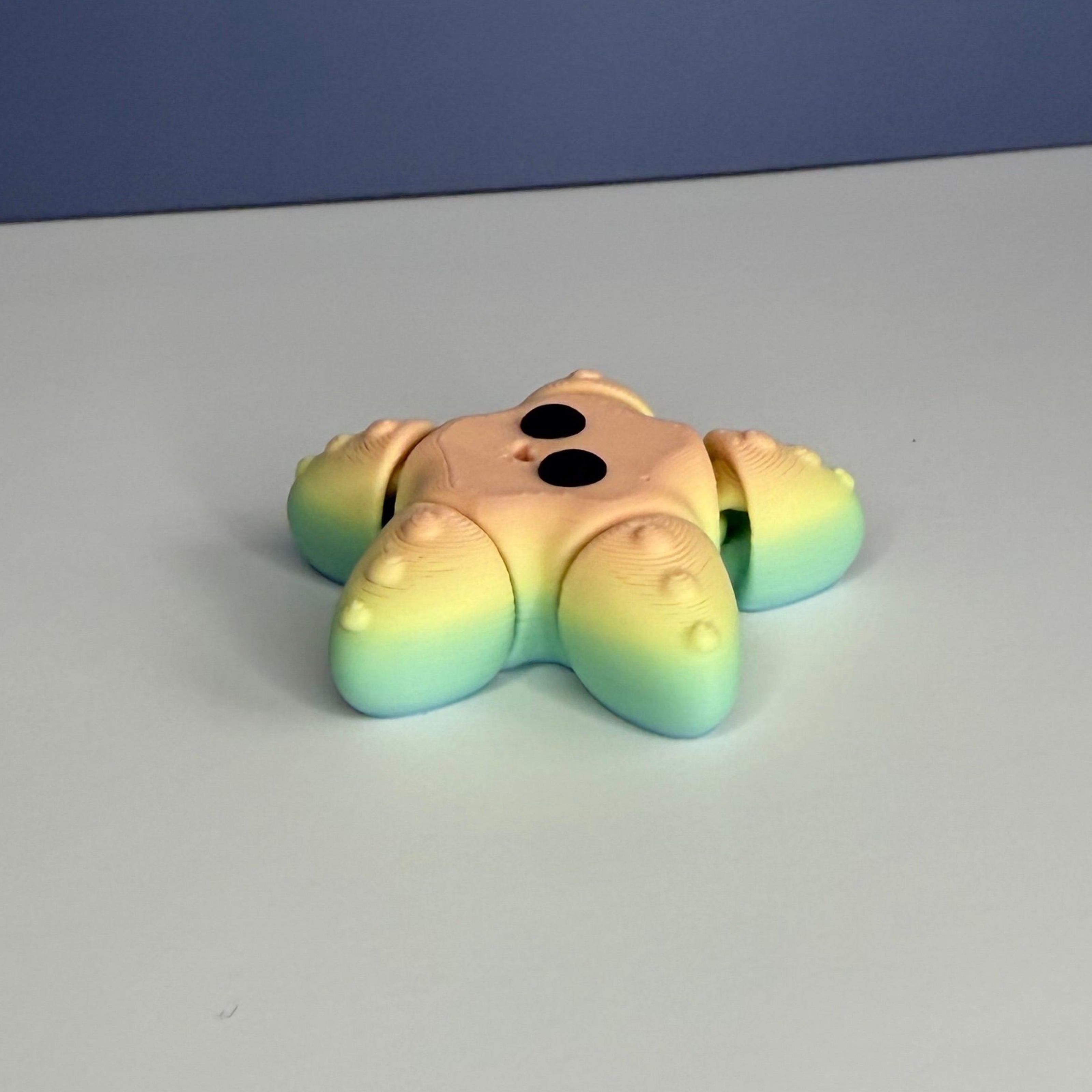 Side of a smiling star-shaped figure with a gradient rainbow color pattern and black eyes on a blue and white background