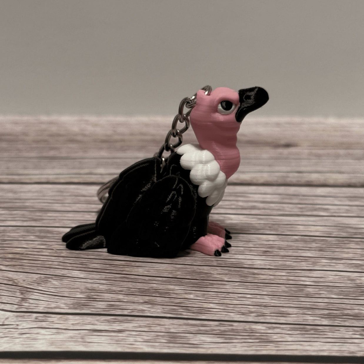 Right side of a keychain shaped like a cartoon vulture on a wooden surface 