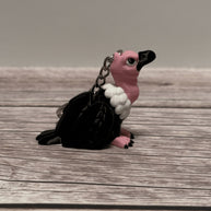 Right side of a keychain shaped like a cartoon vulture on a wooden surface 
