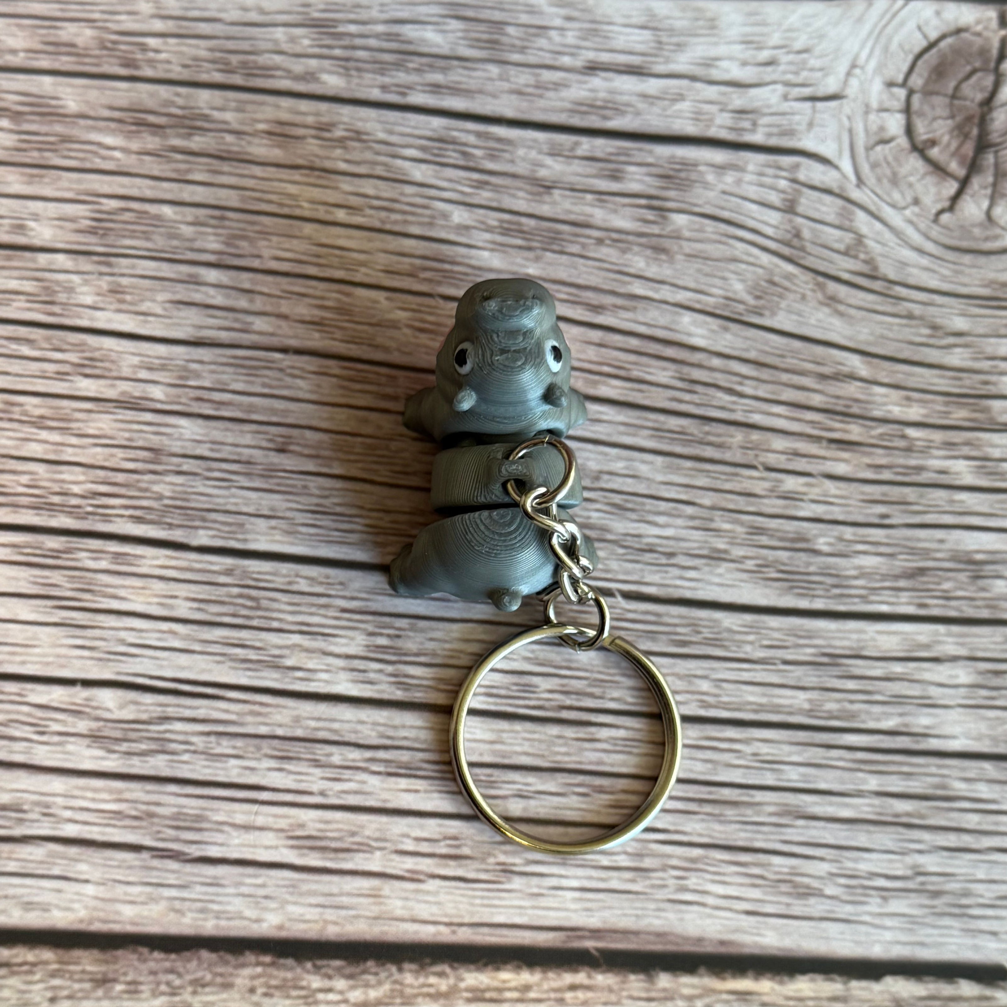 Top of a 3D printed gray and pink hippo-shaped keychain on a wooden surface