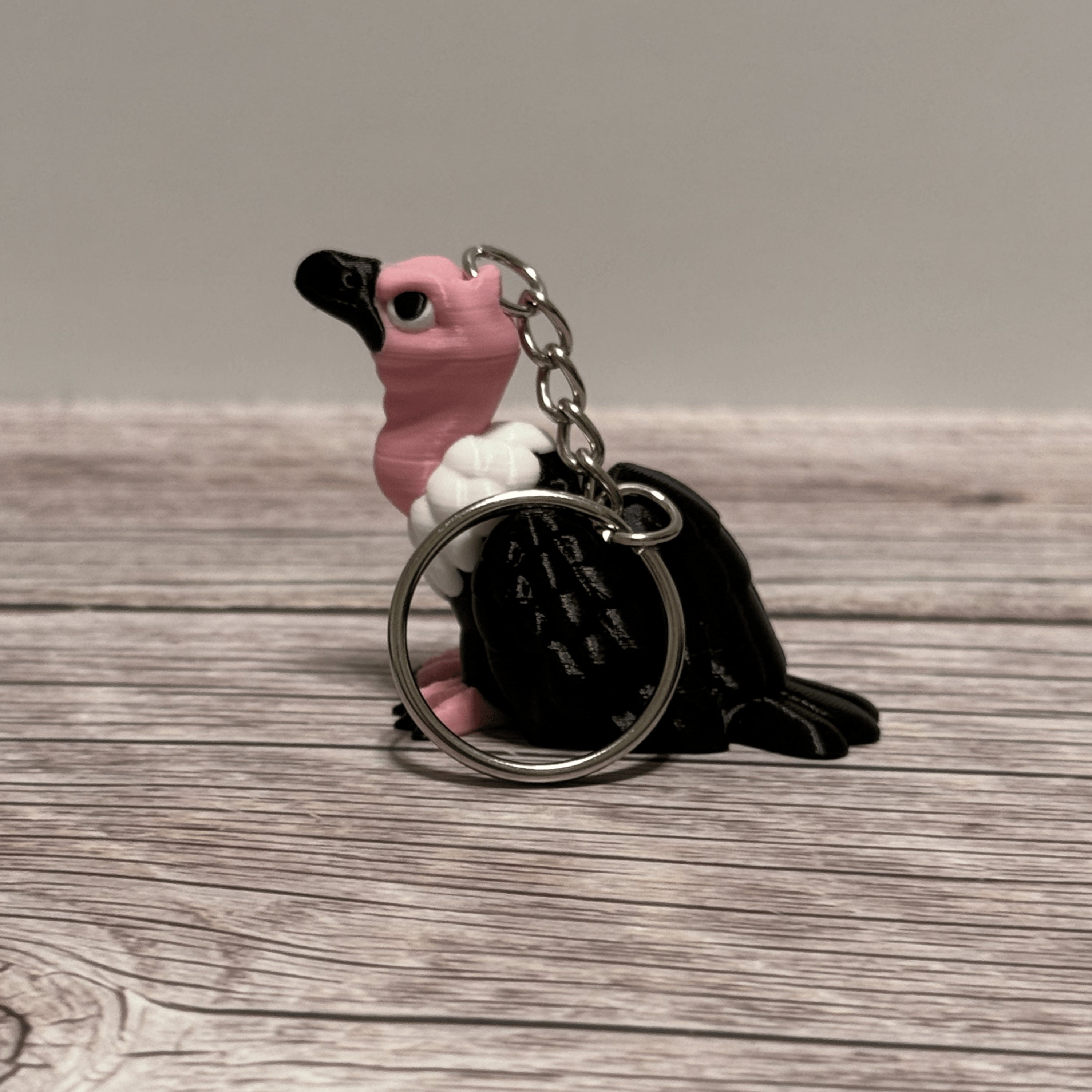 Left side of a keychain shaped like a cartoon vulture on a wooden surface 