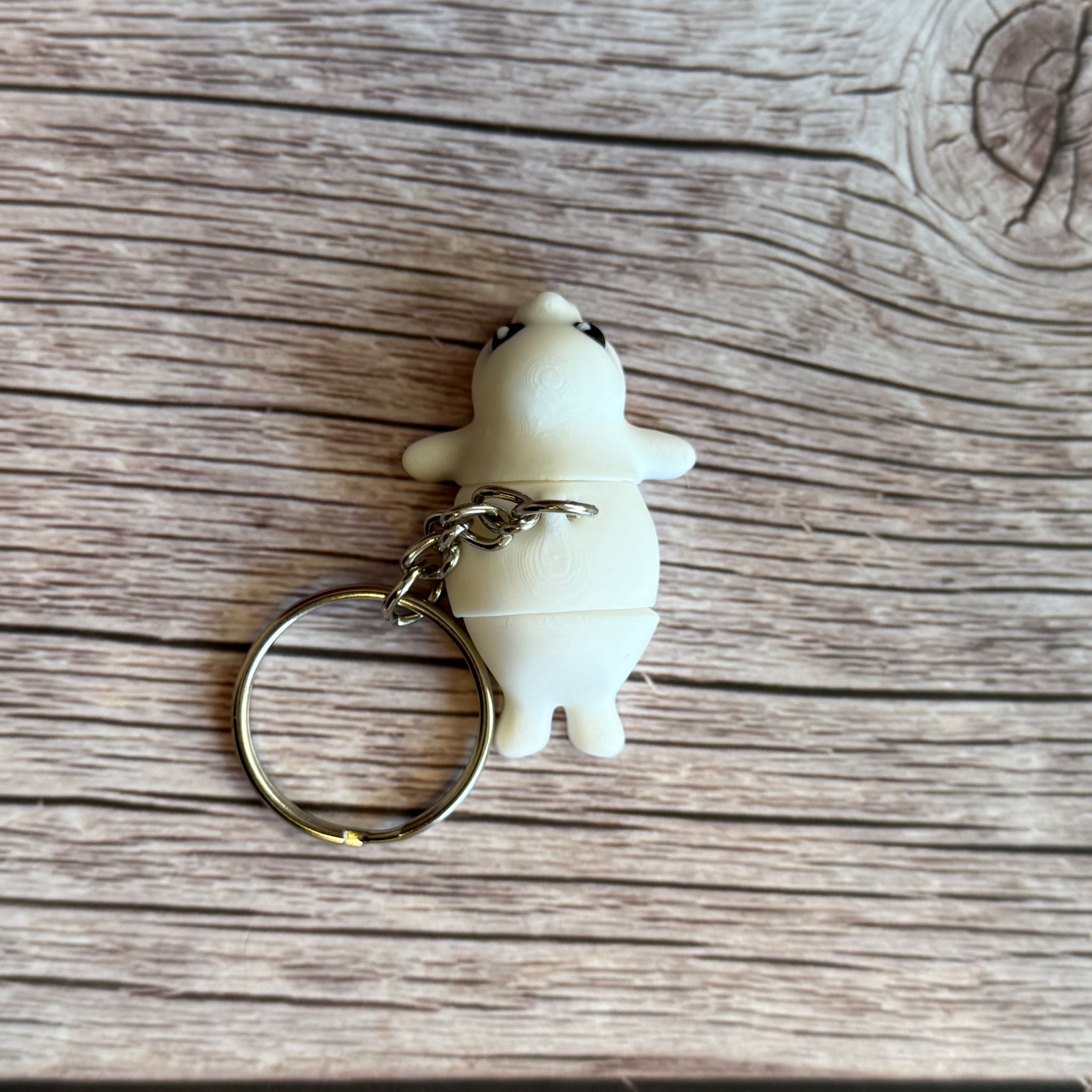 Top of a 3D printed white seal-shaped keychain on a wooden surface