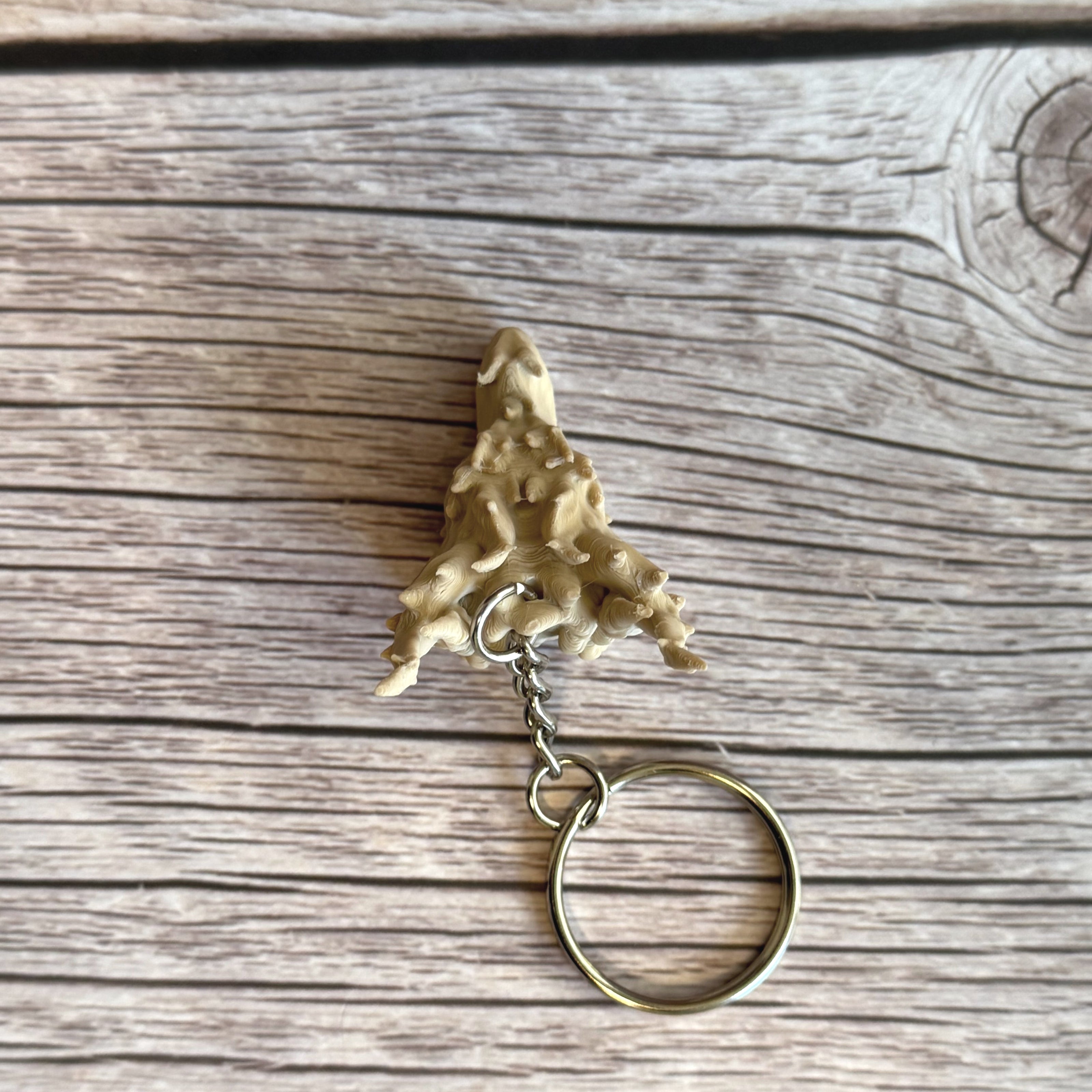 Top of a 3D printed beige dragon head keychain on a wooden surface
