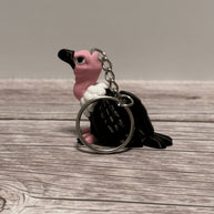 Left side of a keychain shaped like a cartoon vulture on a wooden surface 