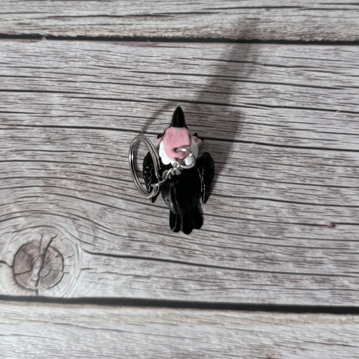 Top side of a keychain shaped like a cartoon vulture on a wooden surface 