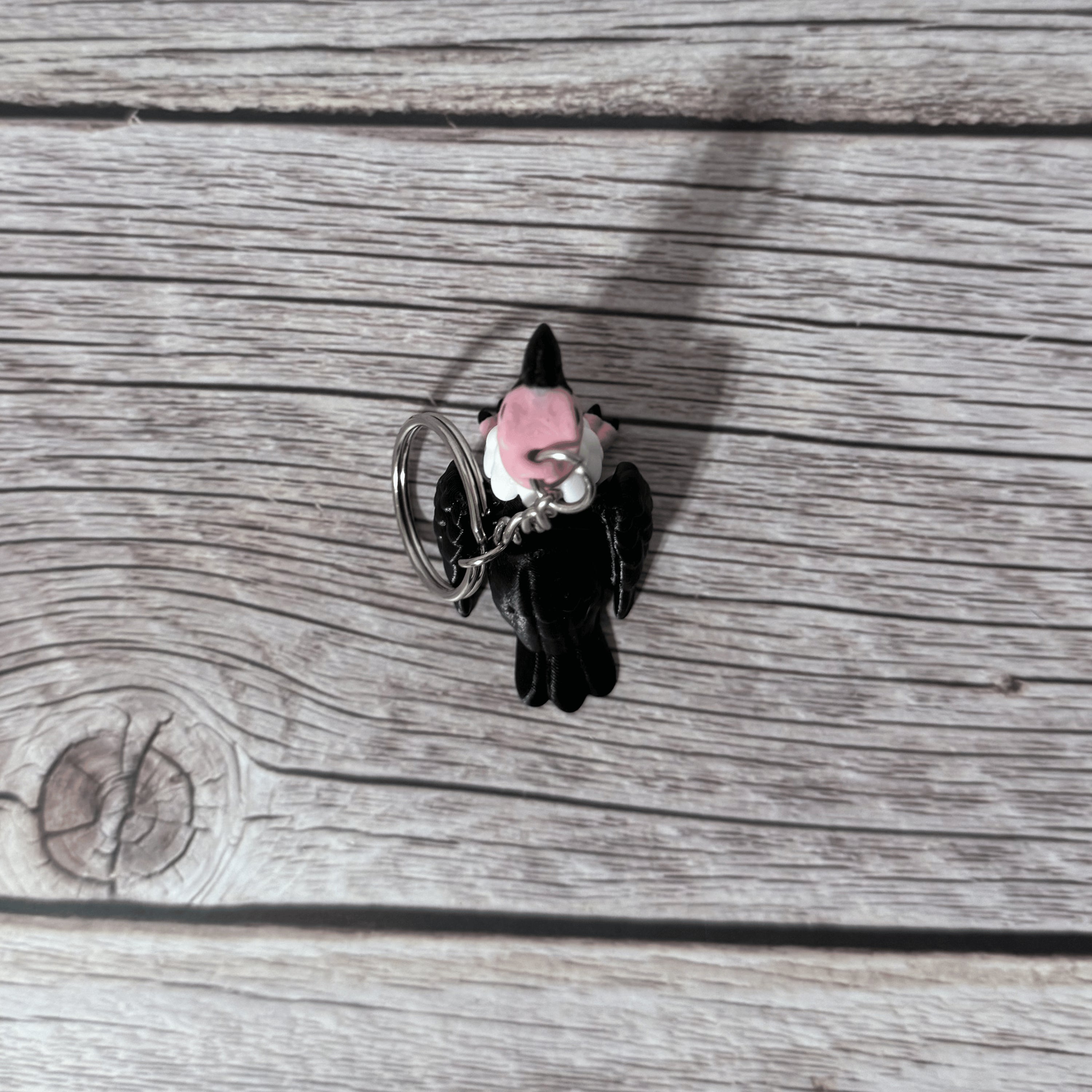 Top side of a keychain shaped like a cartoon vulture on a wooden surface 