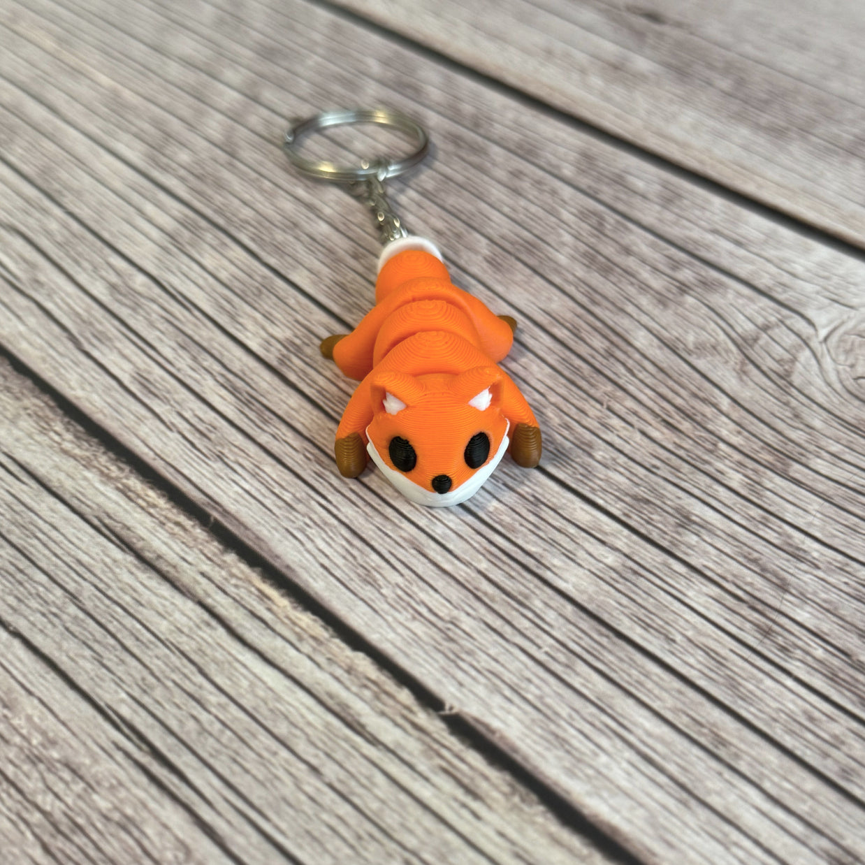 3D printed orange fox-shaped keychain on a wooden surface