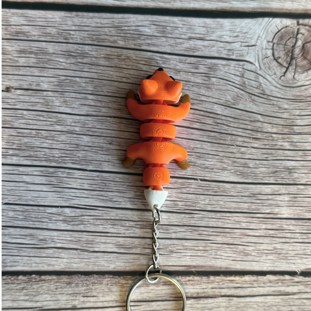 Top of a 3D printed orange fox-shaped keychain on a wooden surface