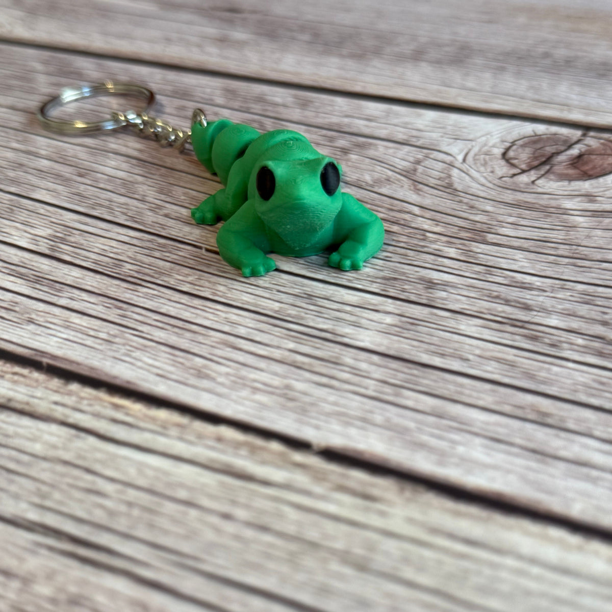 3D printed green lizard-shaped keychain on a wooden surface