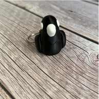 3D printed black and white crow-shaped keychain on a wooden surface