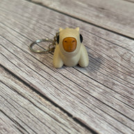 3D printed beige capybara-shaped keychain on a wooden surface