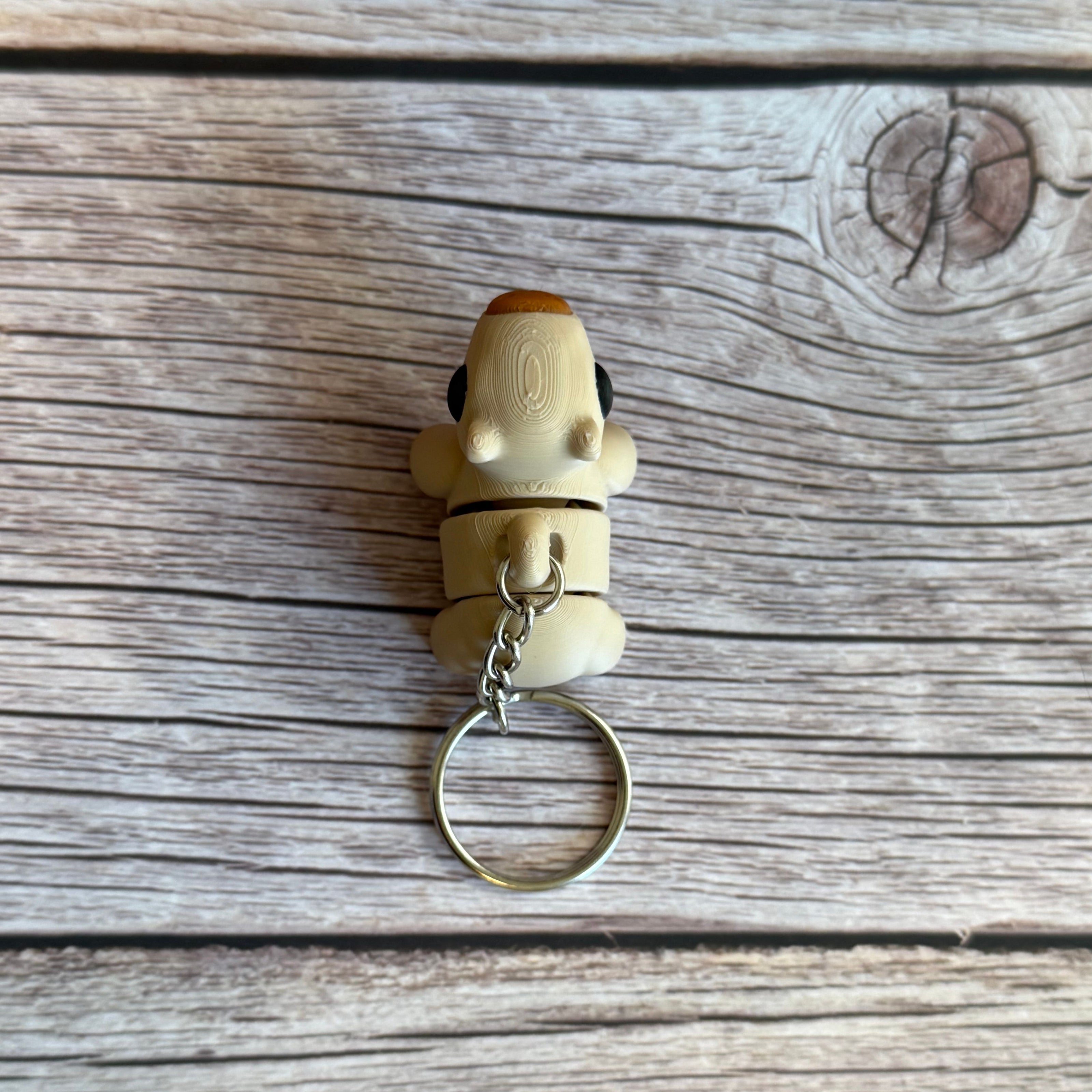 Top of a 3D printed beige capybara-shaped keychain on a wooden surface