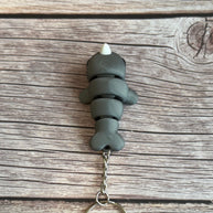 Top of a 3D printed gray narwhal-shaped keychain on a wooden surface