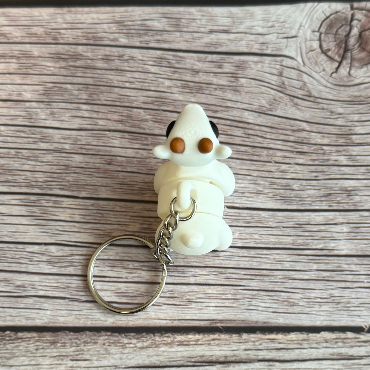 Top of a 3D printed white goat-shaped keychain with brown horns on a wooden surface