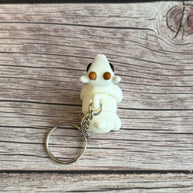 Top of a 3D printed white goat-shaped keychain with brown horns on a wooden surface