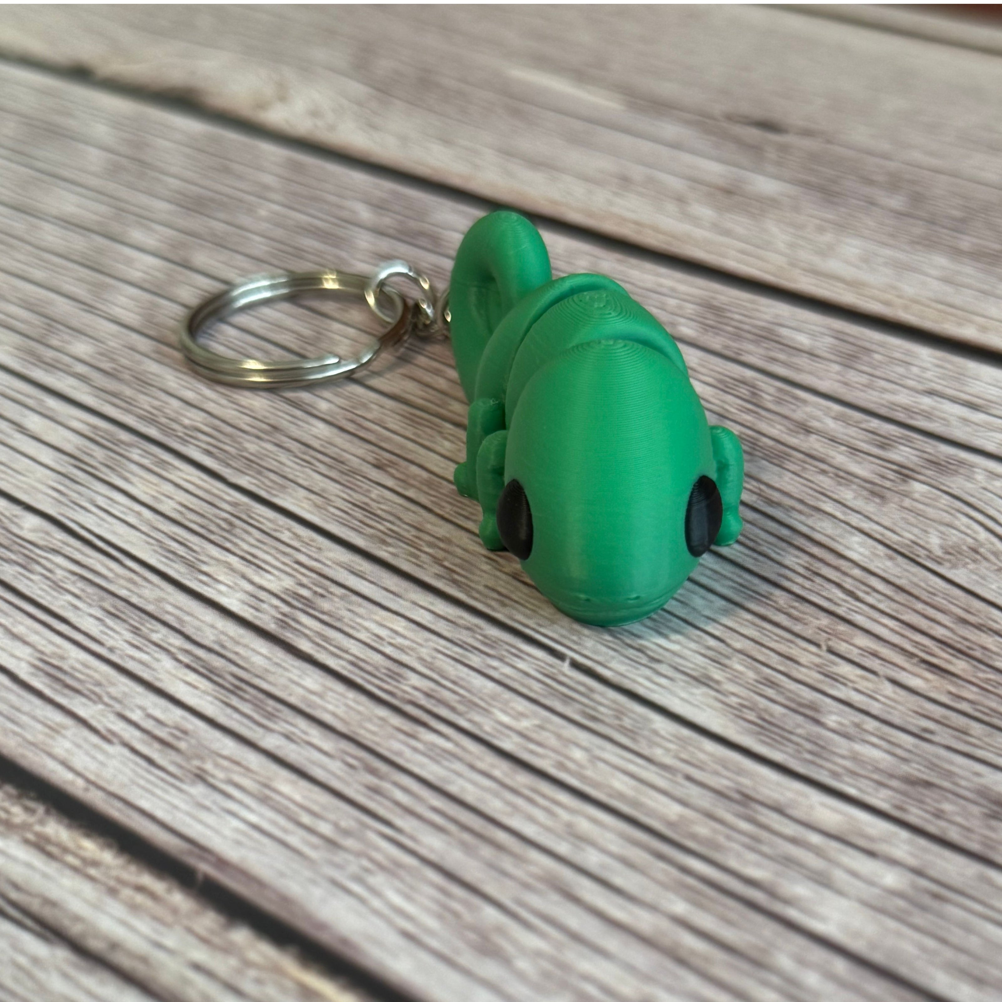 3D printed green chameleon-shaped keychain on a wooden surface