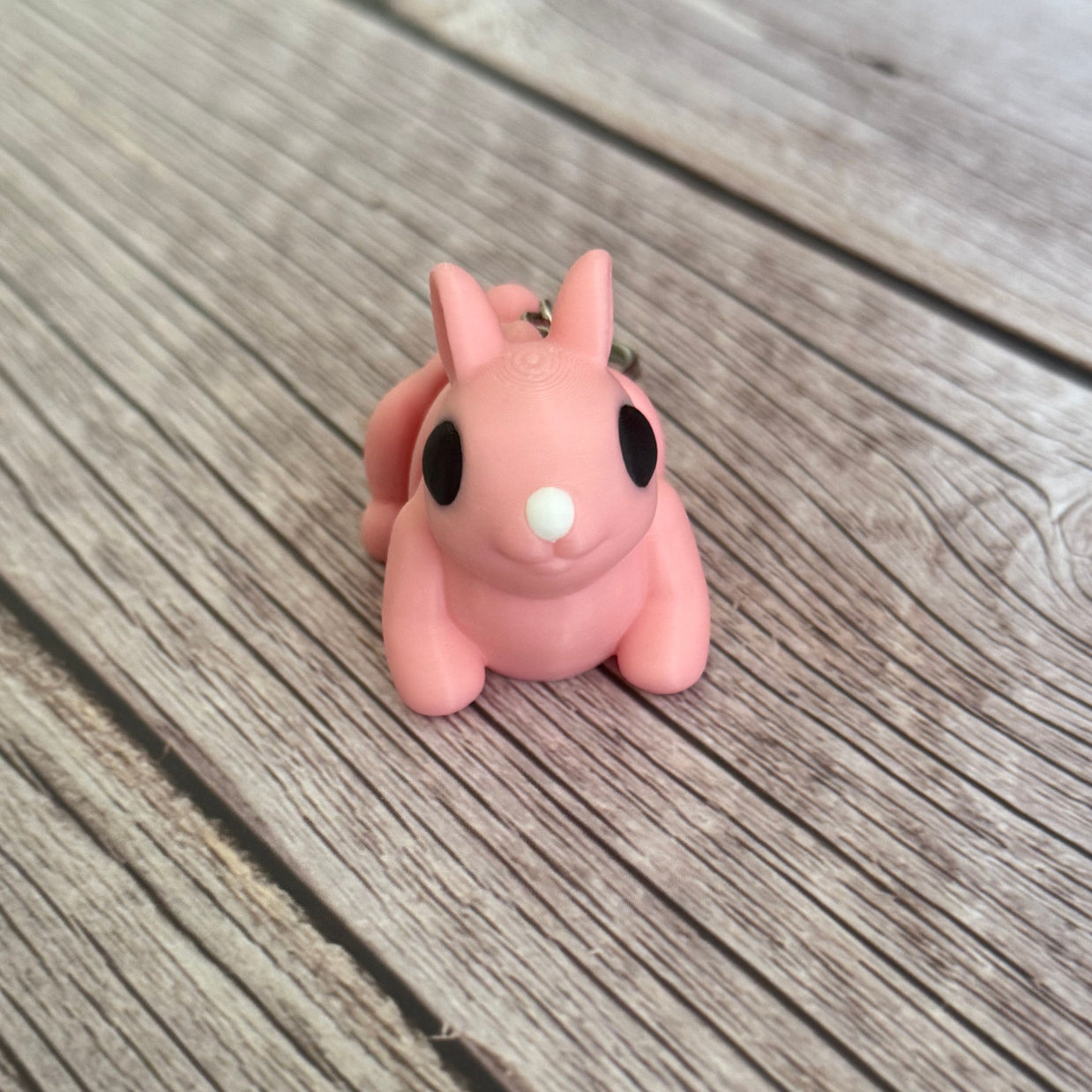 3D printed pink bunny-shaped keychain on a wooden surface