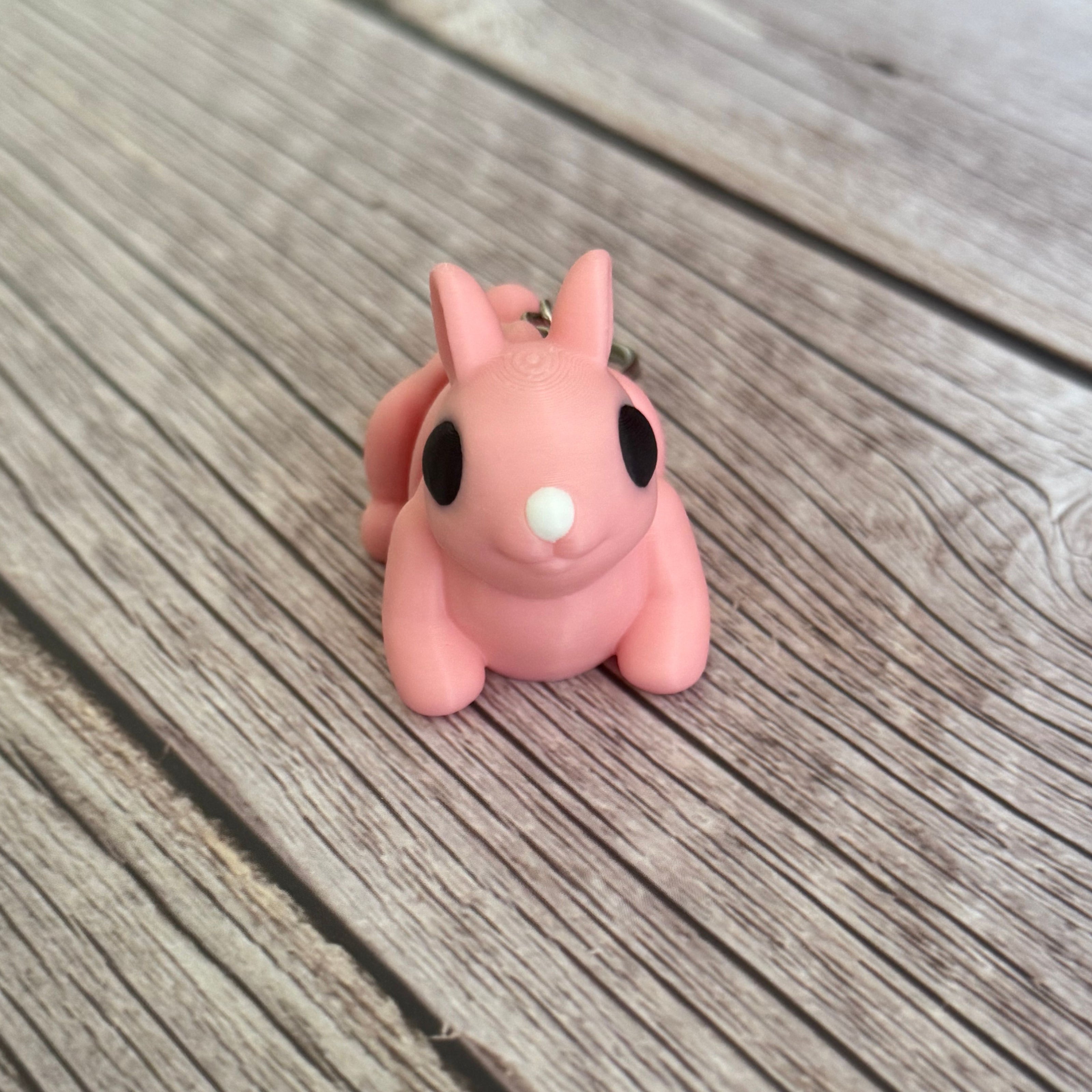 3D printed pink bunny-shaped keychain on a wooden surface