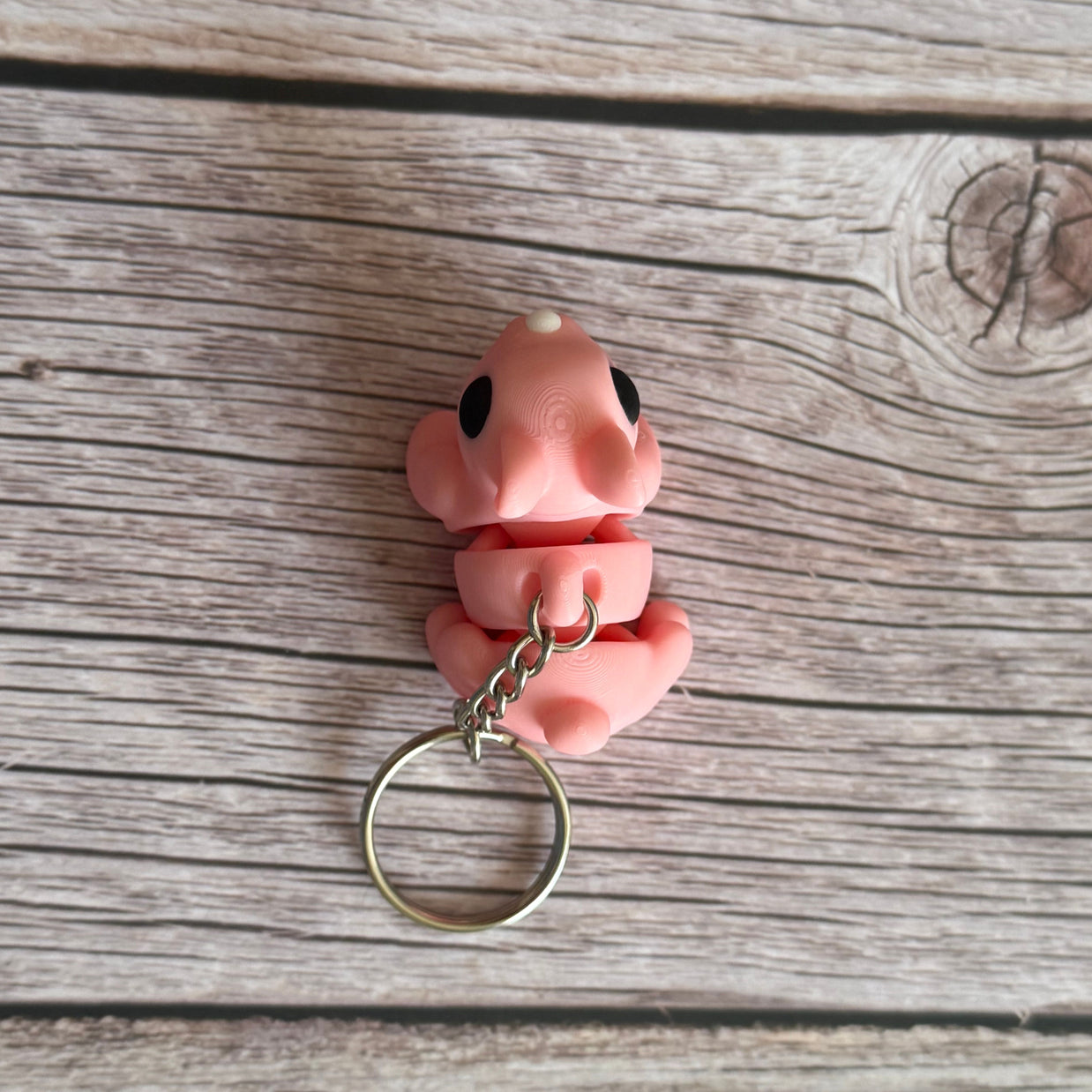 Top of a 3D printed pink bunny-shaped keychain on a wooden surface