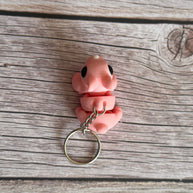 Top of a 3D printed pink bunny-shaped keychain on a wooden surface
