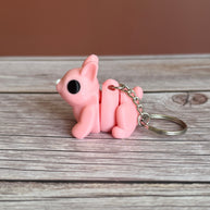Side of a 3D printed pink bunny-shaped keychain on a wooden surface