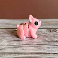 Side of a 3D printed pink bunny-shaped keychain on a wooden surface