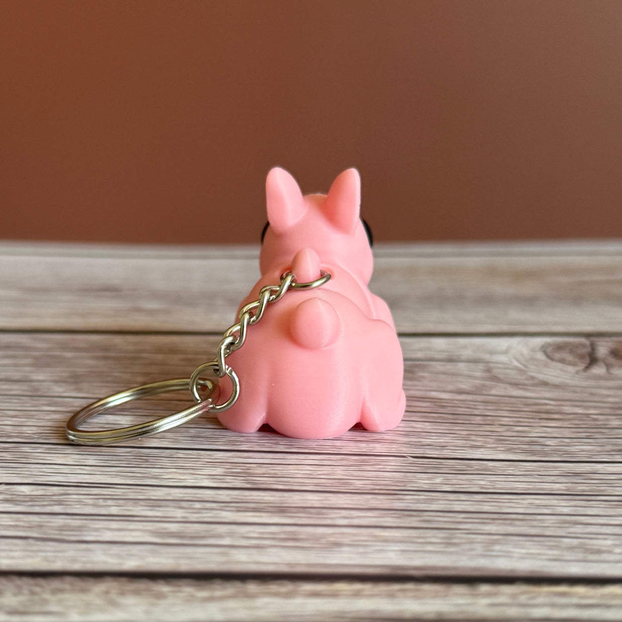 Back of a 3D printed pink bunny-shaped keychain on a wooden surface